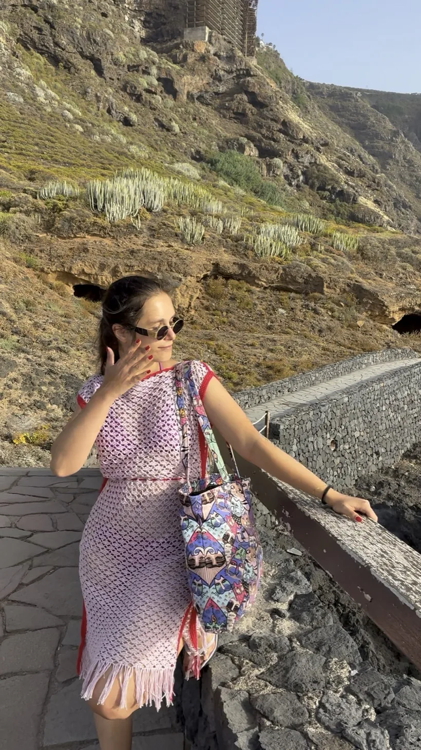Model wearing the Rojas Beach Cover-Up with red side borders and fringe, on a coastal path in Tenerife